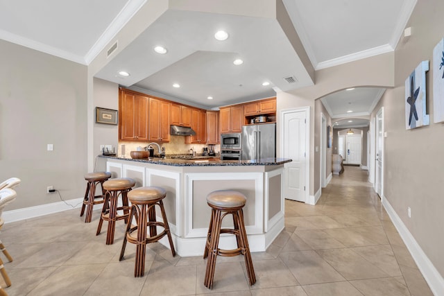 kitchen featuring a kitchen breakfast bar, decorative backsplash, dark stone counters, and appliances with stainless steel finishes