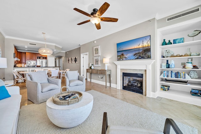 tiled living room featuring a fireplace, ceiling fan, built in features, and ornamental molding