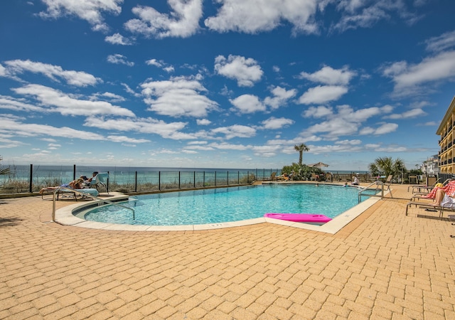 view of pool with a water view and a patio