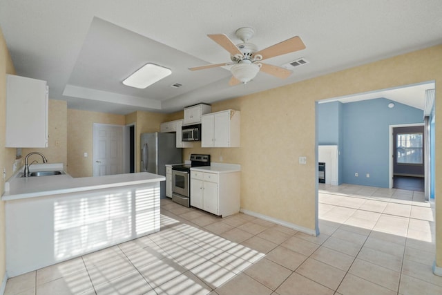 kitchen with appliances with stainless steel finishes, a raised ceiling, sink, light tile patterned floors, and white cabinetry