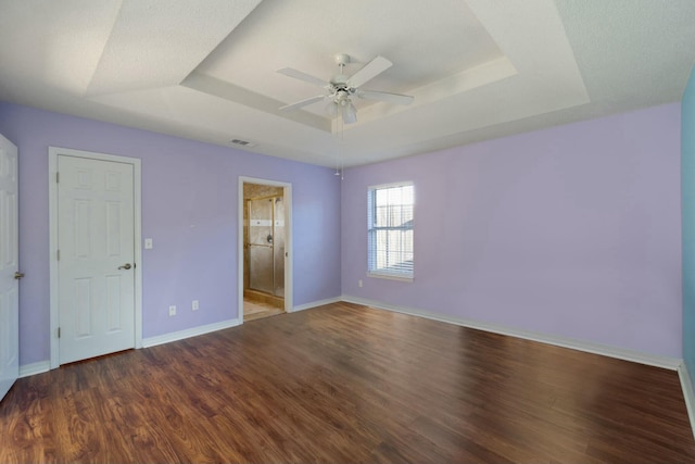 interior space featuring a raised ceiling, ceiling fan, and dark hardwood / wood-style floors