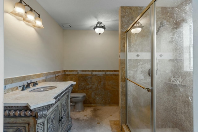 bathroom with walk in shower, vanity, toilet, and tile walls