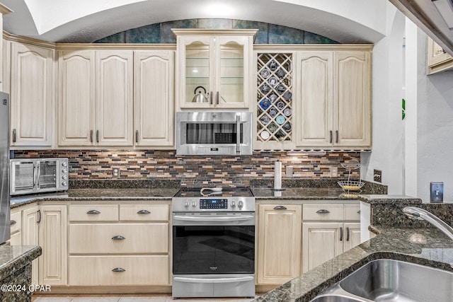 kitchen featuring dark stone counters, appliances with stainless steel finishes, backsplash, and sink