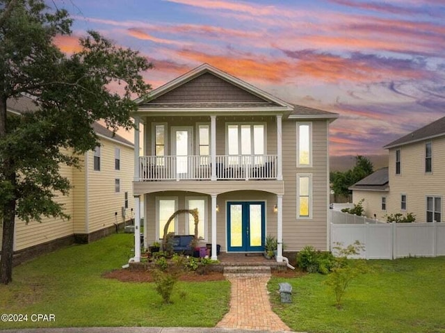 view of front of house featuring a lawn, french doors, and a balcony