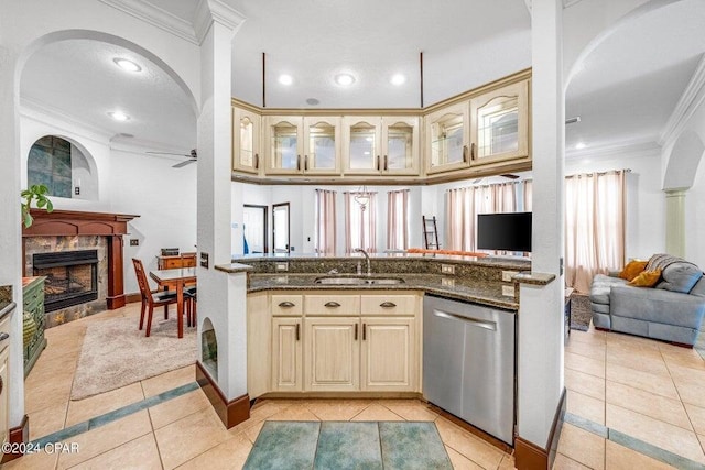 kitchen featuring sink, dark stone countertops, stainless steel dishwasher, and light tile patterned floors