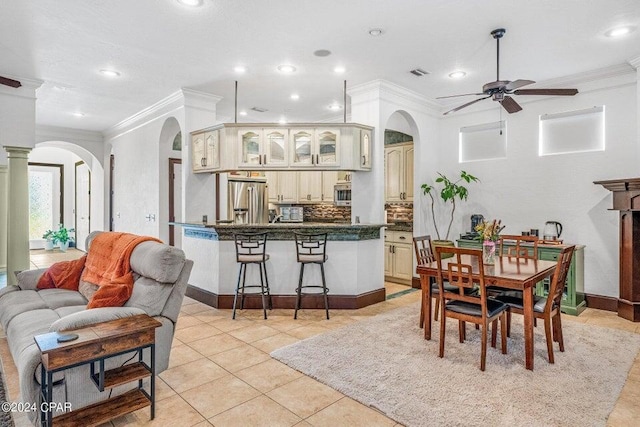 tiled dining room with ceiling fan, ornamental molding, and decorative columns