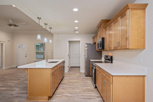 kitchen featuring appliances with stainless steel finishes, ceiling fan, sink, hanging light fixtures, and an island with sink