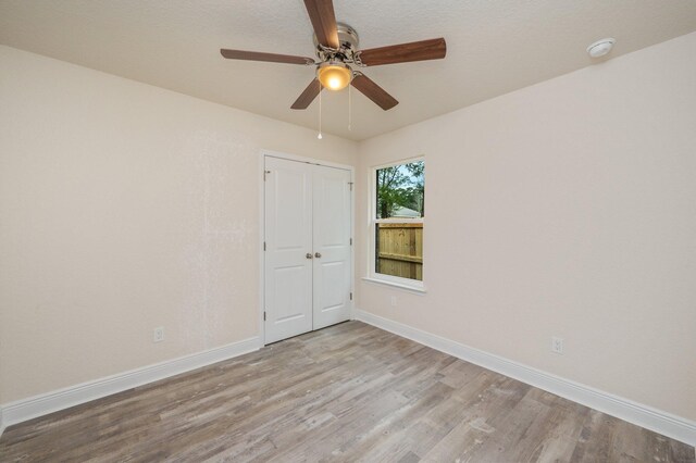 empty room with ceiling fan and light hardwood / wood-style floors