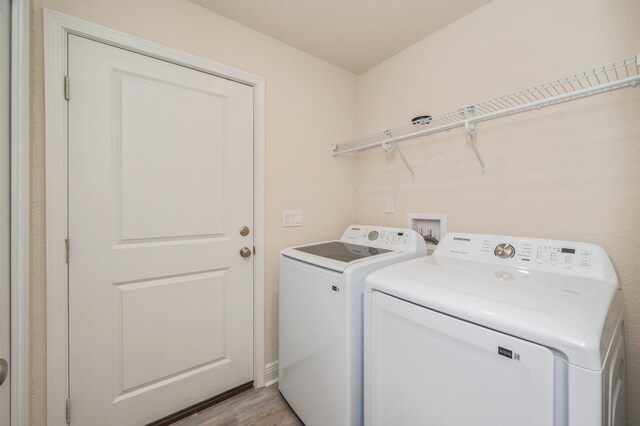 clothes washing area with light hardwood / wood-style floors and washing machine and clothes dryer