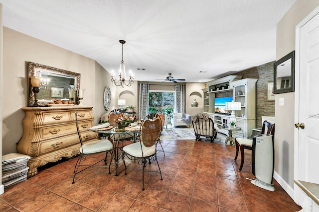 dining area with ceiling fan with notable chandelier, a textured ceiling, and dark tile patterned floors