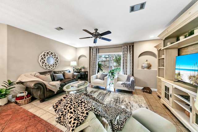 living room with ceiling fan, a textured ceiling, and light tile patterned floors