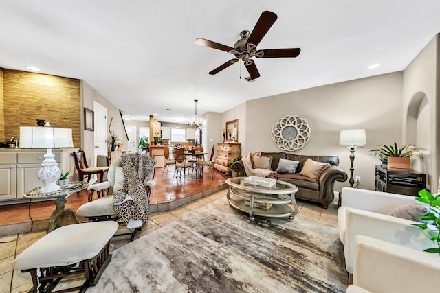 tiled living room featuring ceiling fan with notable chandelier