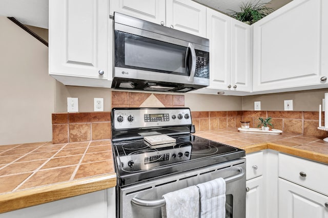 kitchen with stainless steel appliances, tile countertops, and white cabinetry