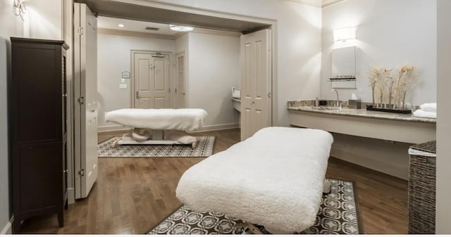 bathroom featuring hardwood / wood-style floors, ornamental molding, and sink