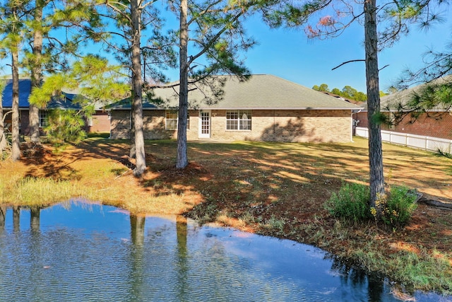 rear view of house with a water view and a lawn