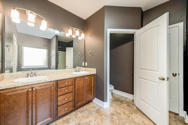 bathroom with a sink, baseboards, toilet, and double vanity