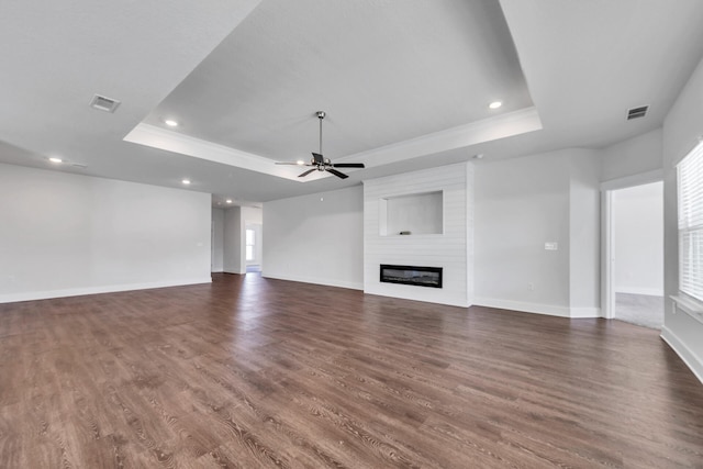 unfurnished living room with ceiling fan, dark hardwood / wood-style flooring, a fireplace, and a tray ceiling