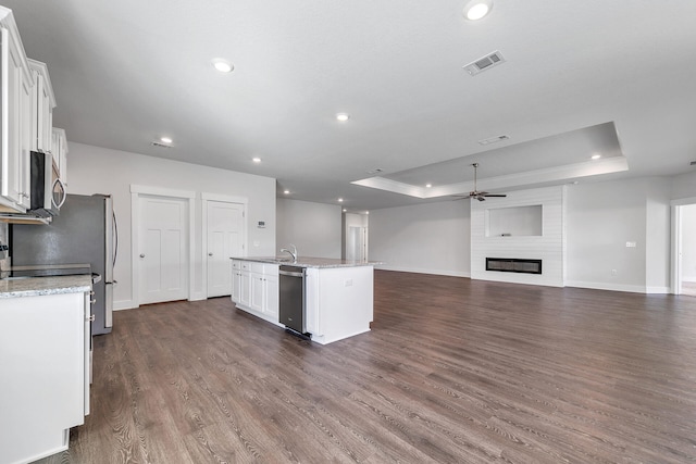 kitchen featuring white cabinets, appliances with stainless steel finishes, a raised ceiling, and an island with sink