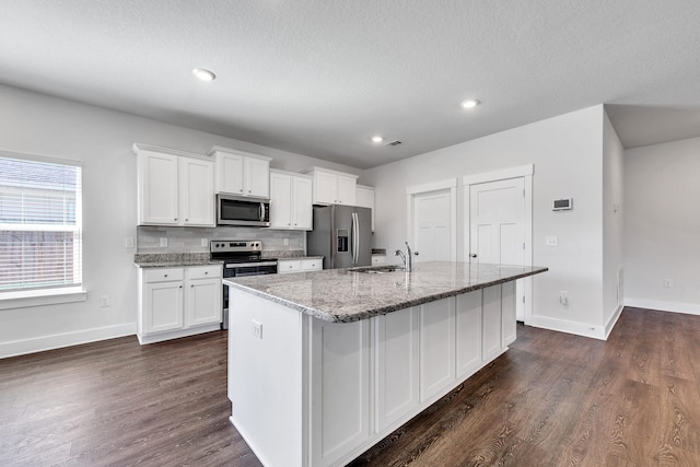 kitchen with white cabinets, stainless steel appliances, a kitchen island with sink, and sink