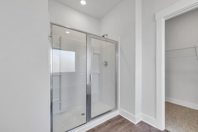 bathroom with wood-type flooring and a shower with shower door