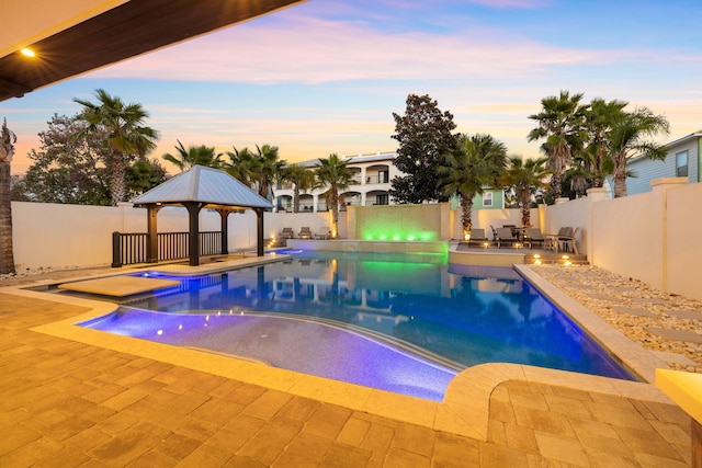 pool at dusk with a gazebo and a patio area