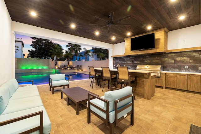 patio terrace at dusk with outdoor lounge area, ceiling fan, exterior kitchen, a grill, and a fenced in pool