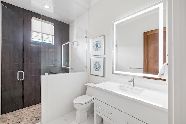 bathroom with tile patterned floors, vanity, tiled shower, and toilet