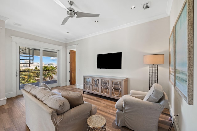 living room featuring hardwood / wood-style floors, ceiling fan, and crown molding