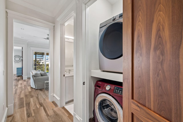 washroom featuring stacked washer / dryer, light hardwood / wood-style floors, and ornamental molding