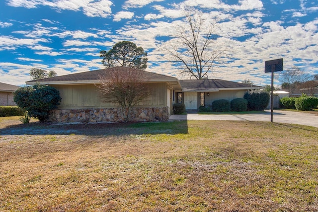 ranch-style house featuring a front yard, stone siding, and concrete driveway