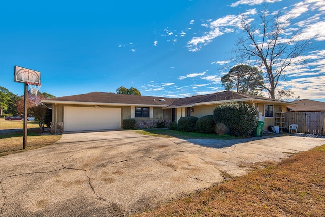 ranch-style home featuring concrete driveway, stone siding, an attached garage, fence, and a front yard