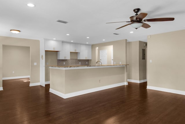 kitchen featuring dark wood finished floors, visible vents, backsplash, white cabinets, and light stone countertops