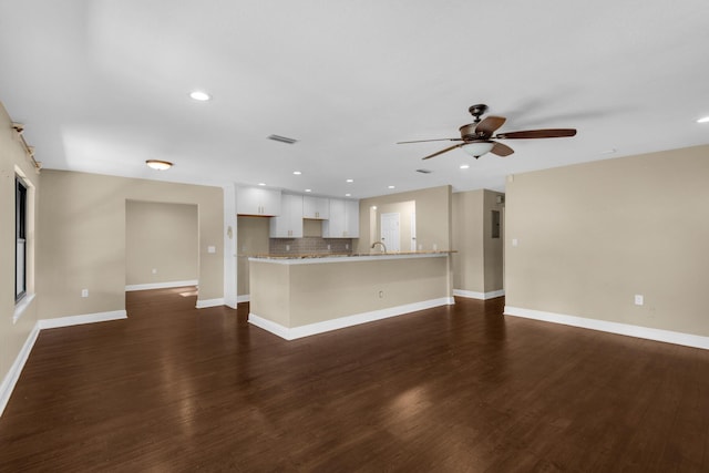 unfurnished living room with baseboards, visible vents, dark wood finished floors, and a ceiling fan