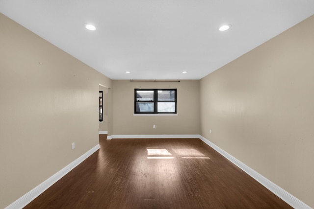 spare room featuring recessed lighting, dark wood finished floors, and baseboards