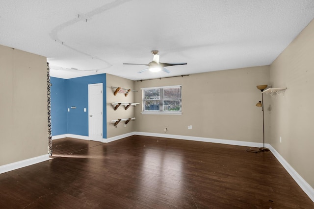 empty room with ceiling fan, a textured ceiling, wood finished floors, and baseboards