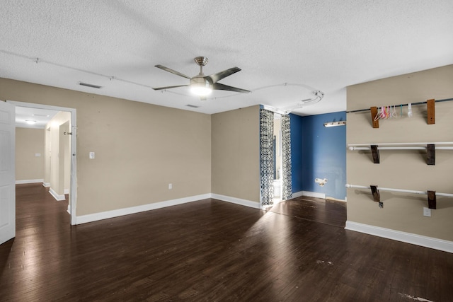 empty room with dark wood-style flooring, visible vents, a ceiling fan, a textured ceiling, and baseboards