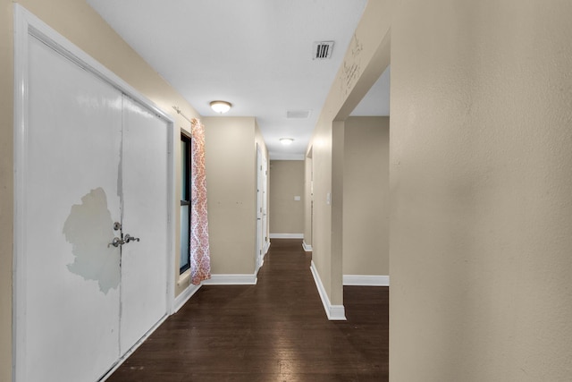 hall with dark wood finished floors, visible vents, and baseboards