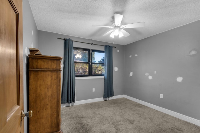 unfurnished room with carpet floors, ceiling fan, baseboards, and a textured ceiling