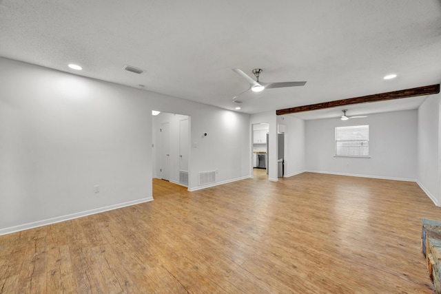 unfurnished living room featuring beam ceiling, ceiling fan, and light wood-type flooring