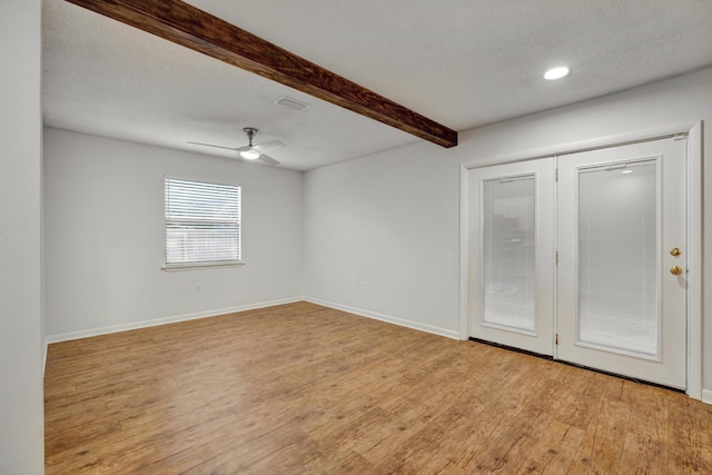 unfurnished room featuring beam ceiling, ceiling fan, a textured ceiling, and light wood-type flooring