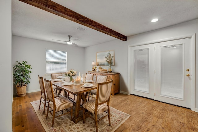 dining room with beamed ceiling, a textured ceiling, light hardwood / wood-style flooring, and ceiling fan