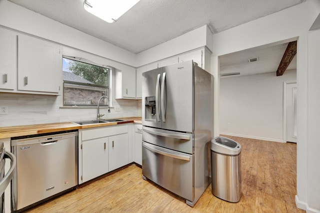 kitchen featuring appliances with stainless steel finishes, white cabinetry, and beam ceiling