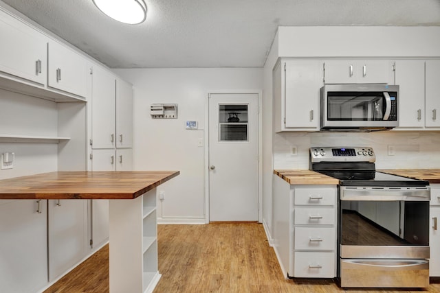 kitchen with butcher block countertops, white cabinetry, stainless steel appliances, and tasteful backsplash