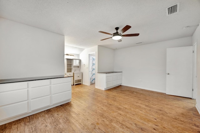 spare room featuring ceiling fan, light wood-type flooring, and a textured ceiling