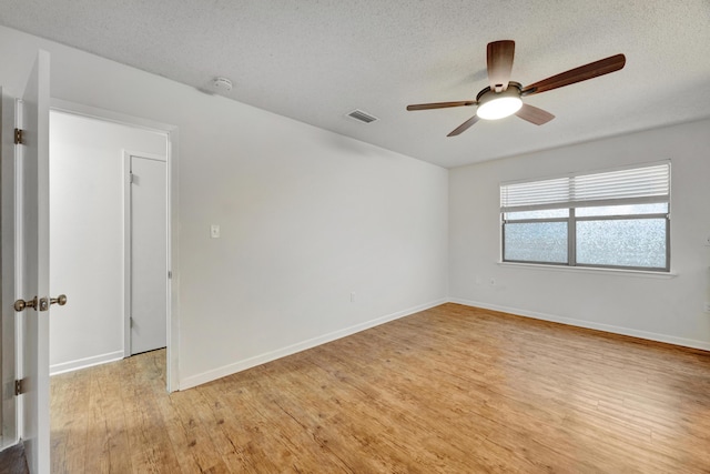 unfurnished room with a textured ceiling, light wood-type flooring, and ceiling fan