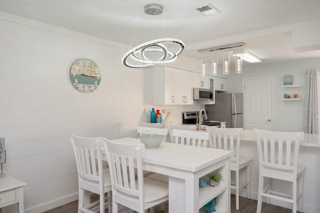 dining space with dark hardwood / wood-style floors, a notable chandelier, and sink