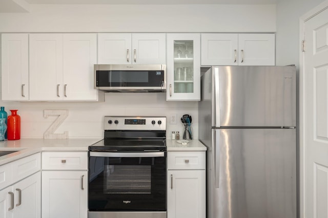 kitchen with decorative backsplash, white cabinetry, and stainless steel appliances