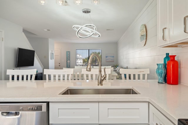 kitchen with pendant lighting, white cabinets, sink, stainless steel dishwasher, and a chandelier