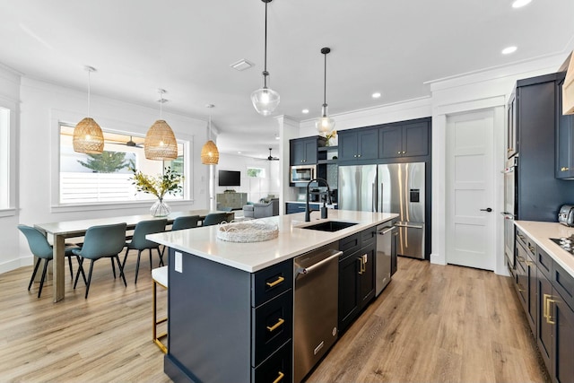 kitchen featuring appliances with stainless steel finishes, pendant lighting, sink, ceiling fan, and a center island with sink