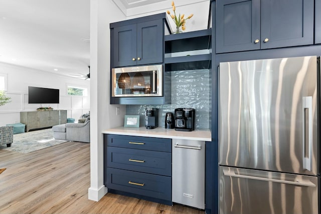 kitchen with stainless steel fridge, blue cabinetry, light hardwood / wood-style floors, and ceiling fan